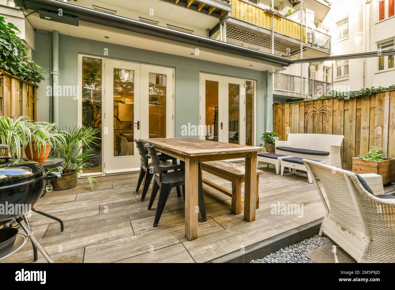 Eine Terrasse mit Stühlen, Tischen und einem Essbereich im Freien auf dem Boden vor einer Tür ist offen Stockfoto