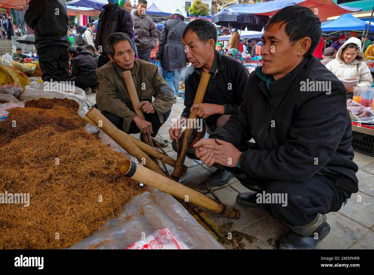 BAC Ha, Vietnam - 18. Dezember 2022: Männer, die auf dem Wochenmarkt von Bac Ha in Vietnam Tabak rauchen. Stockfoto