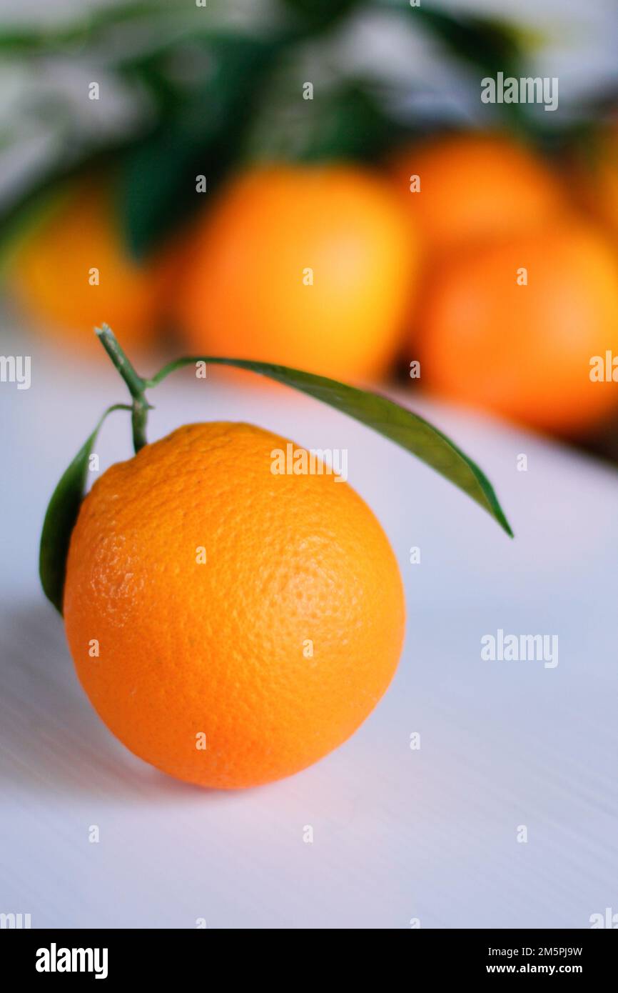 Eine vertikale Nahaufnahme einer isolierten Mandarine mit grünen Blättern auf einer weißen Oberfläche Stockfoto