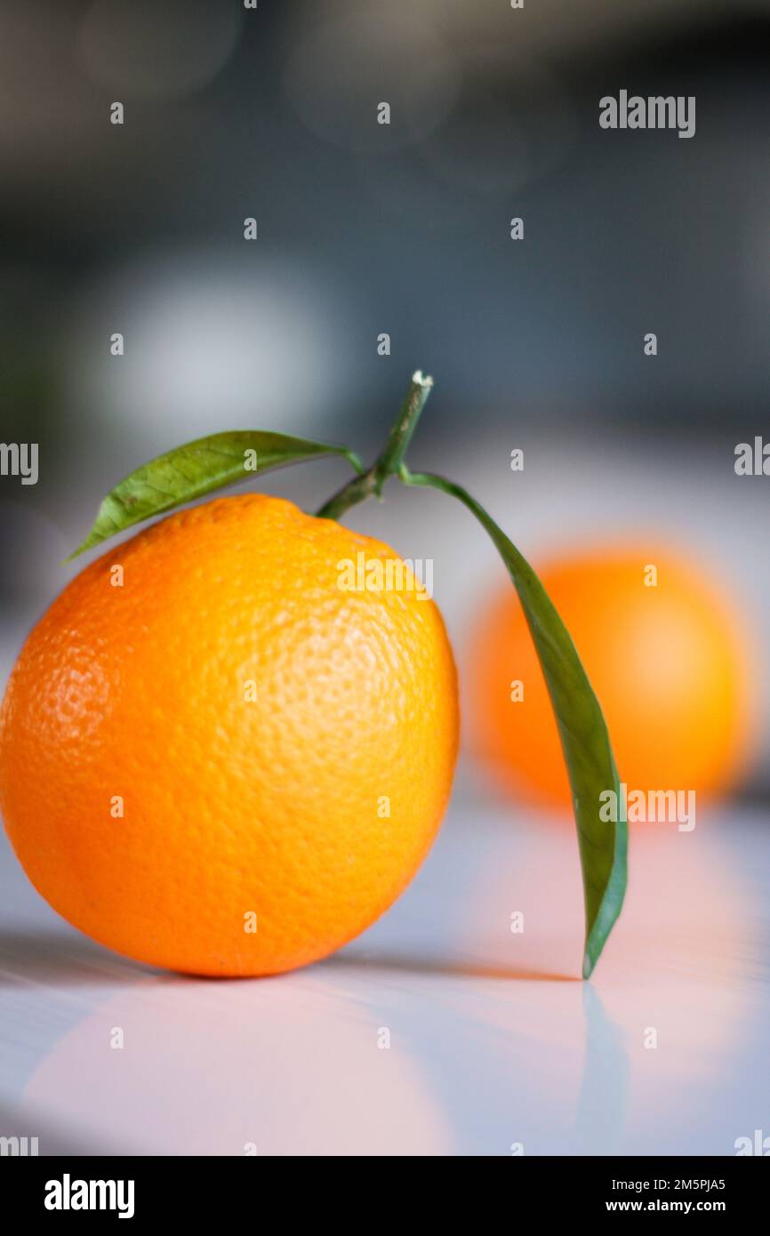 Eine vertikale Nahaufnahme einer isolierten Mandarine mit grünen Blättern auf einer weißen Oberfläche Stockfoto