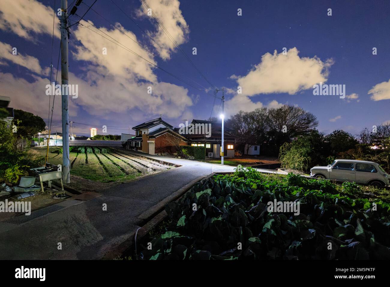 Japanisches Haus und kleine Felder mit weißen Wolken am dunkelblauen Himmel bei Nacht Stockfoto