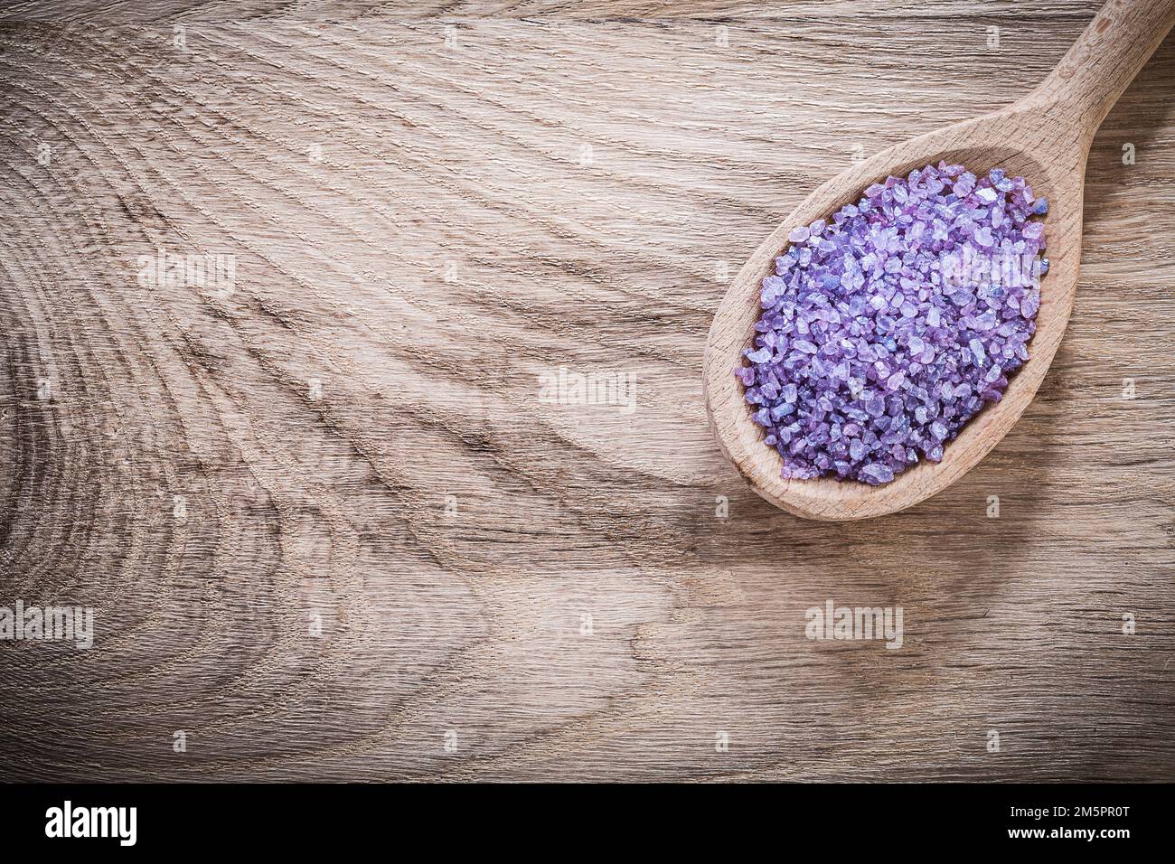 Lavendelkuratives Meersalz in Holzlöffel auf Holzbrett Kopier-Spa-Behandlungskonzept. Stockfoto