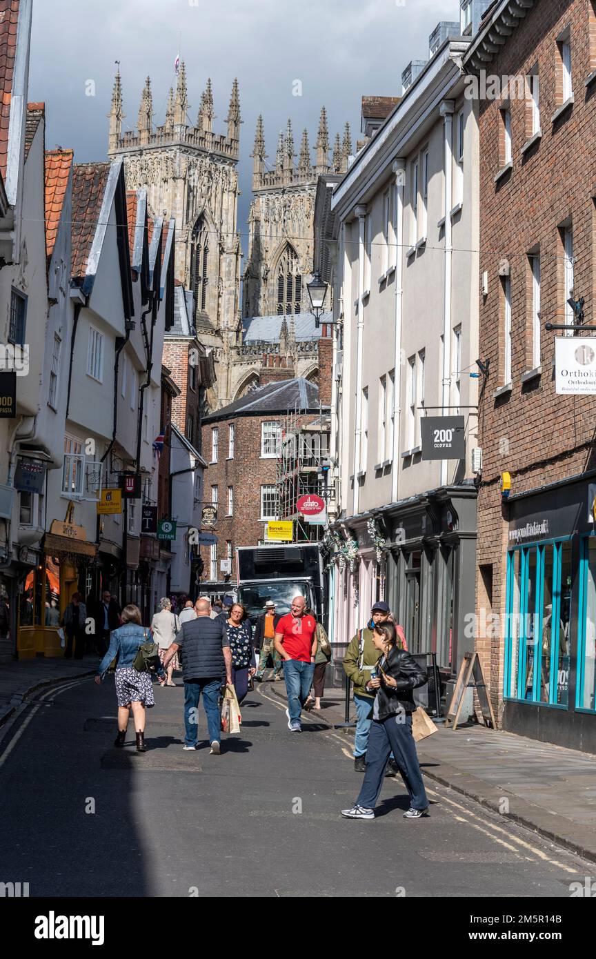 Die schmale Einkaufsstraße Low Petergate, eine mittelalterliche Straße, blickt auf die Türme von York Minister in der Stadt York im Norden Englands. Stockfoto