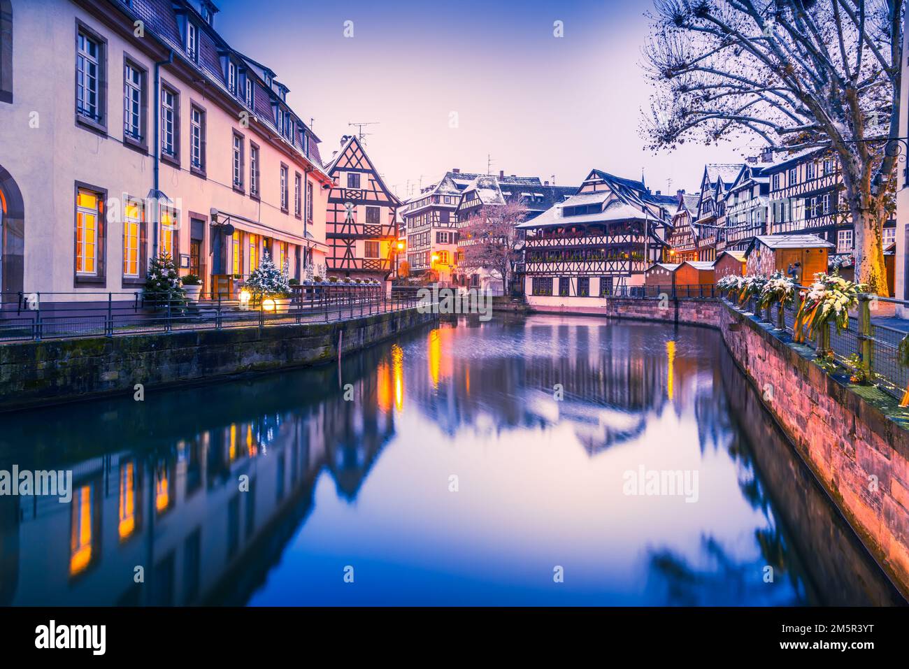 Straßburg, Frankreich. Traditionelle elsässische Stadt mit Fachwerkhäusern, Wasserreflexionen in Petite France während der Dämmerung. Weihnachtsdekoration im Winter Stockfoto