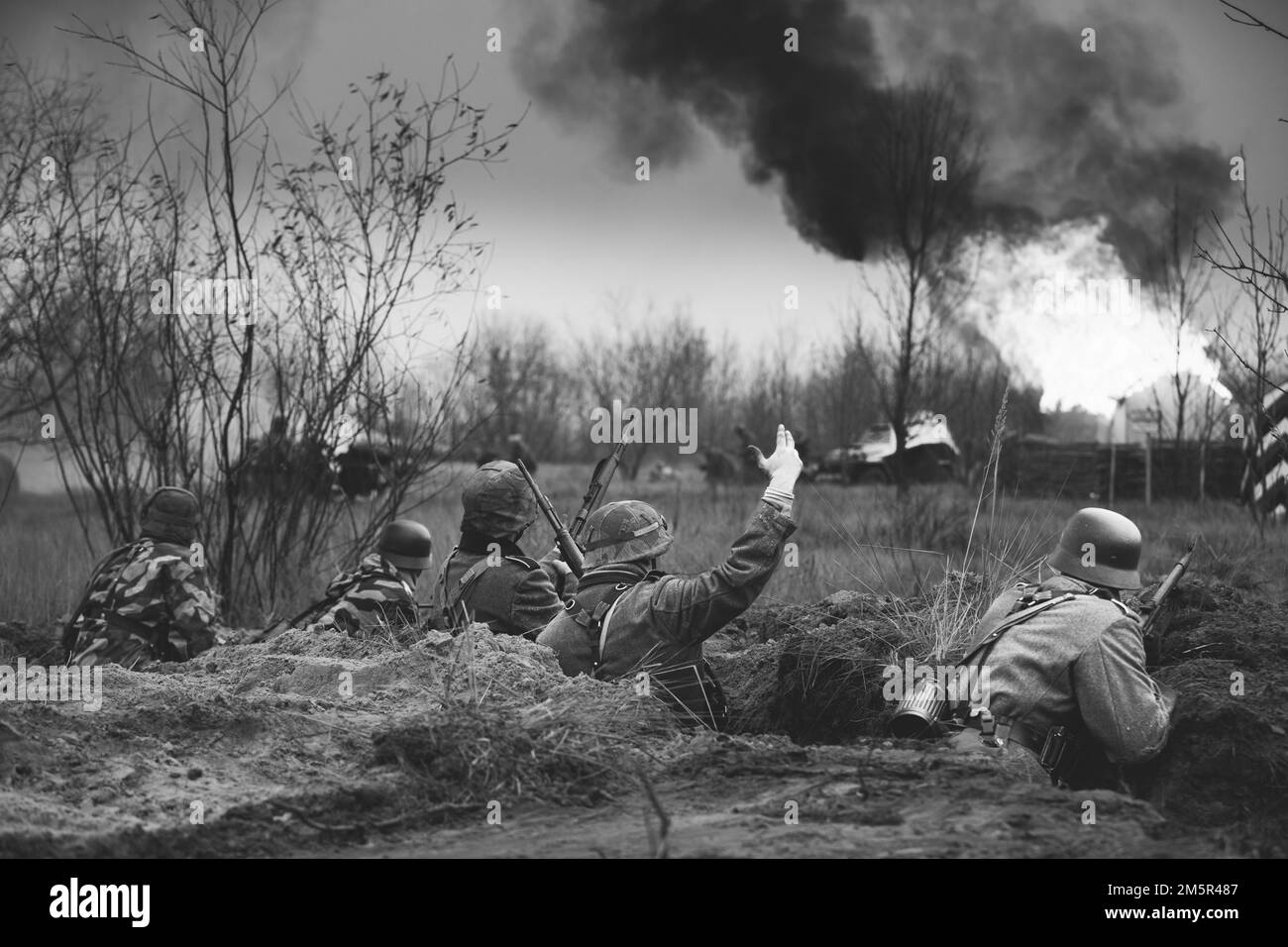 Verteidigungsposition. Nachbemaler bewaffneter Gewehre und gekleidet als deutsche Wehrmacht-Infanterie-Soldaten aus dem Zweiten Weltkrieg, die in Trench defensiv kämpfen. Gebäude Stockfoto