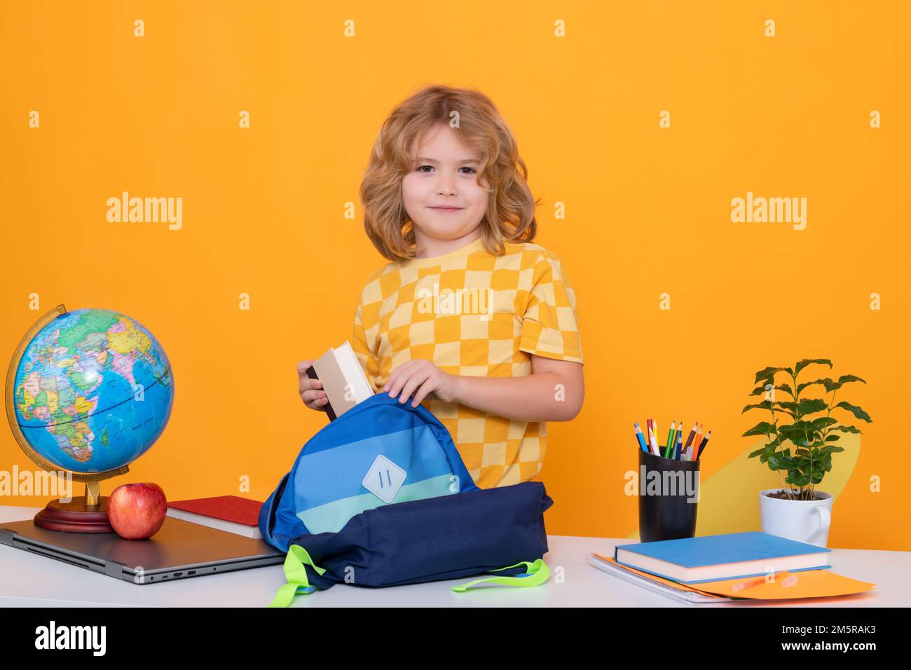 Zurück in die Schule. Das lustige kleine Kind aus der Grundschule packt Schulsachen in einen Rucksack. Schulvorbereitung. Bildung. Kinderstudium und Stockfoto