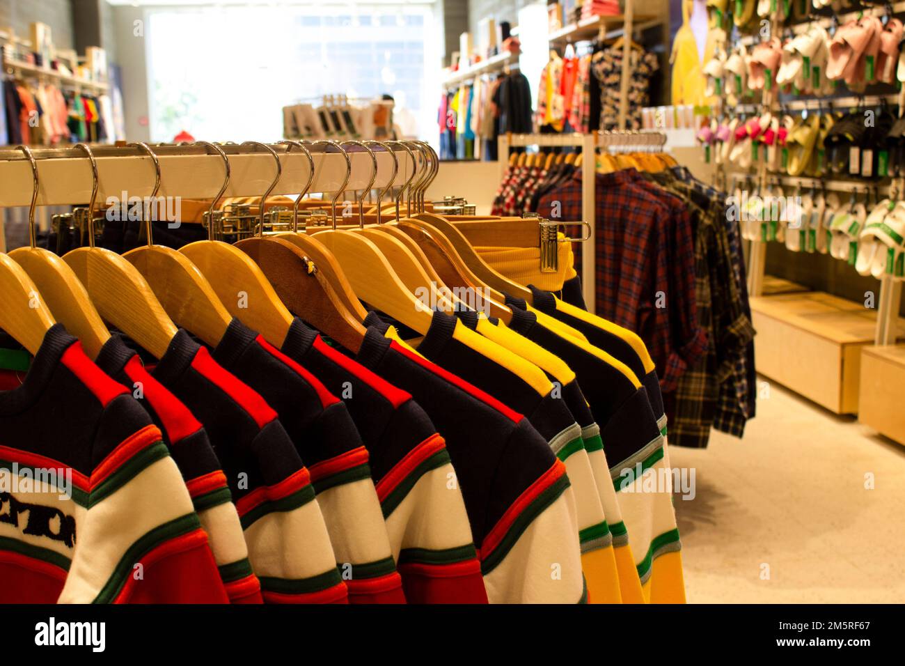 Hemden und Hosen, die an Kleiderbügeln hängen und auf einem Regal in einem modernen Bekleidungsgeschäft angeordnet sind Stockfoto