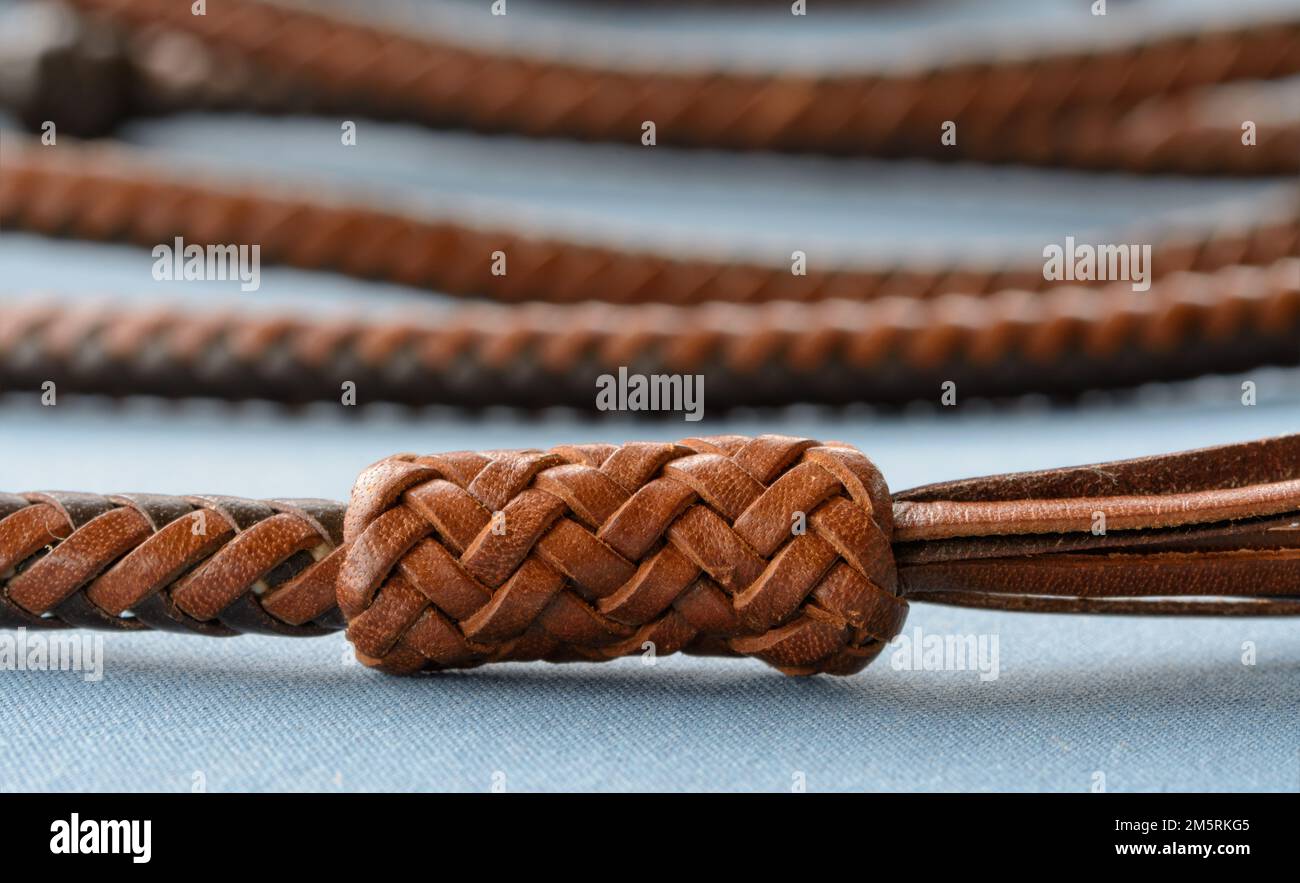 Ein komplizierter, langer Lederknoten, der von einem einzelnen Lederstrang in einem über zwei, unter zwei Mustern, am Ende der handgeflochtenen Lederhandschuhe gebunden ist Stockfoto