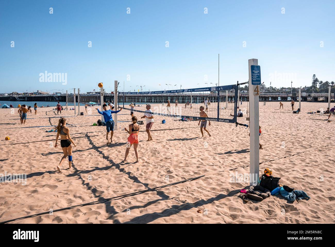 Am Strand spielen Leute Volleyball mit Santa Cruz Wharf im Hintergrund Stockfoto