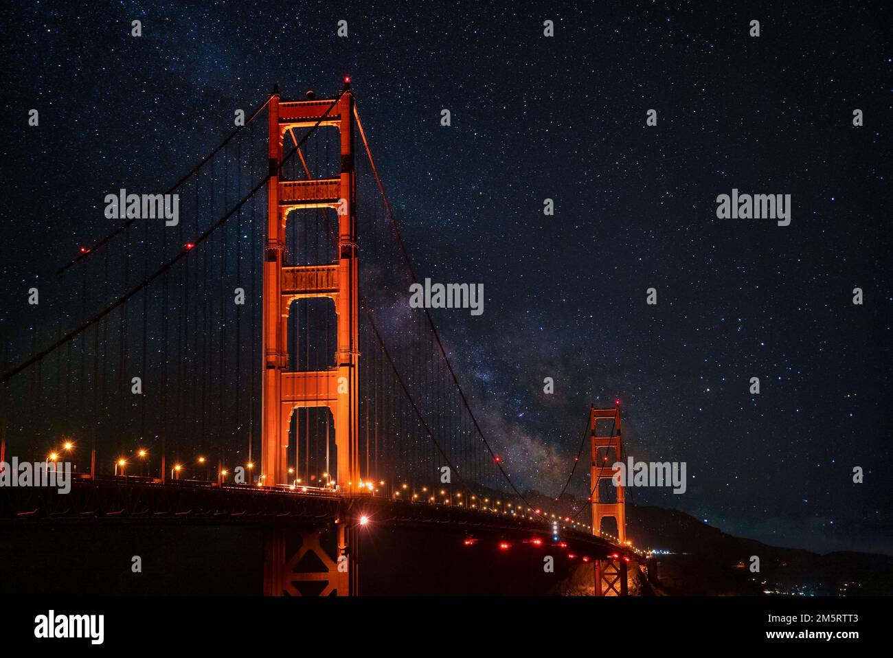 Beleuchtete Golden Gate Hängebrücke unter einem wunderschönen Sternenfeld bei Nacht Stockfoto