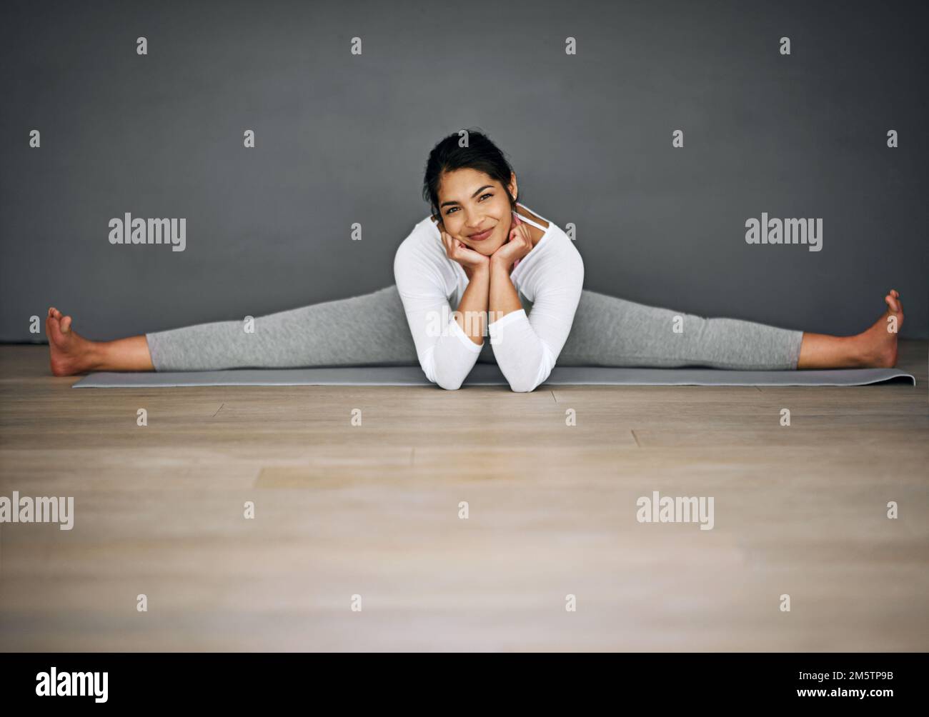 Gesundheit ist Glück. Porträt einer attraktiven jungen Frau, die die Spaltungen in ihrer Yoga-Routine macht. Stockfoto