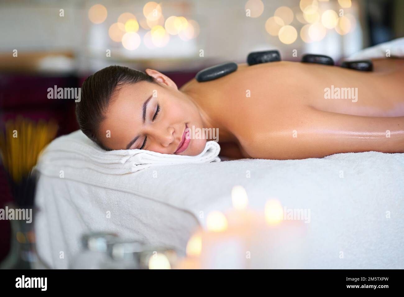 Ihr Zufluchtsort zum Entspannen. Eine junge Frau, die eine Hot-Stone-Massage in einem Spa genießt. Stockfoto
