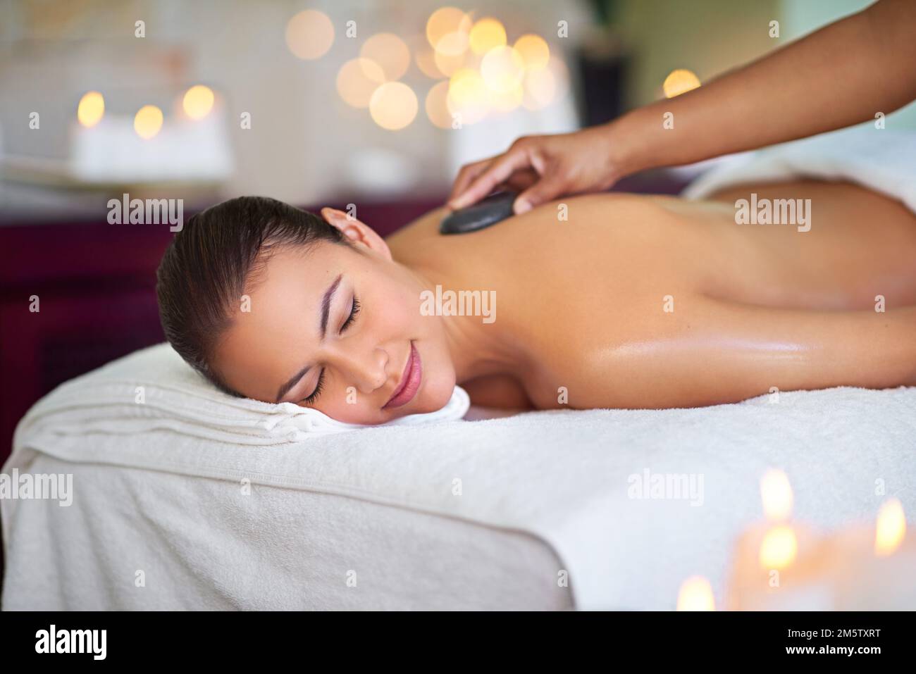 Beruhige dich, beruhige dein Herz. Eine junge Frau, die eine Hot-Stone-Massage in einem Spa genießt. Stockfoto