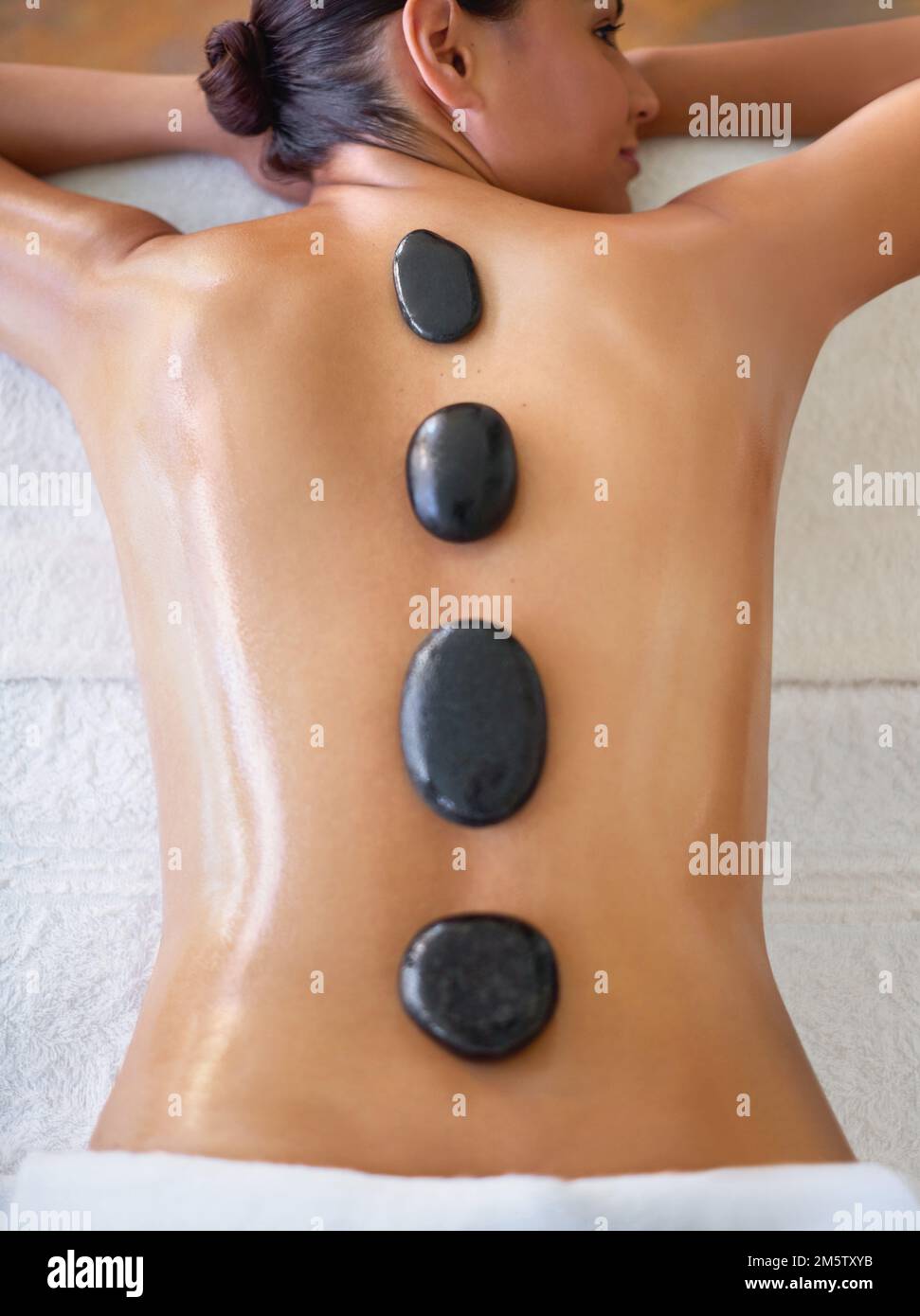 Lassen Sie die Hitze in Ihrem Rücken und Ihren Schultern entspannen. Eine junge Frau, die eine Hot-Stone-Massage in einem Spa genießt. Stockfoto