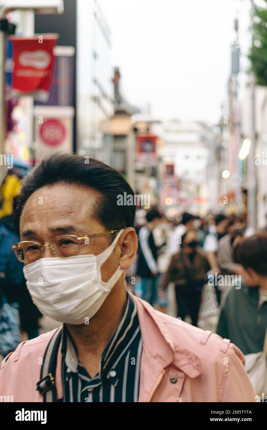 Ein Mann mittleren Alters, der eine Maske auf den Straßen von Harajuku trägt Stockfoto
