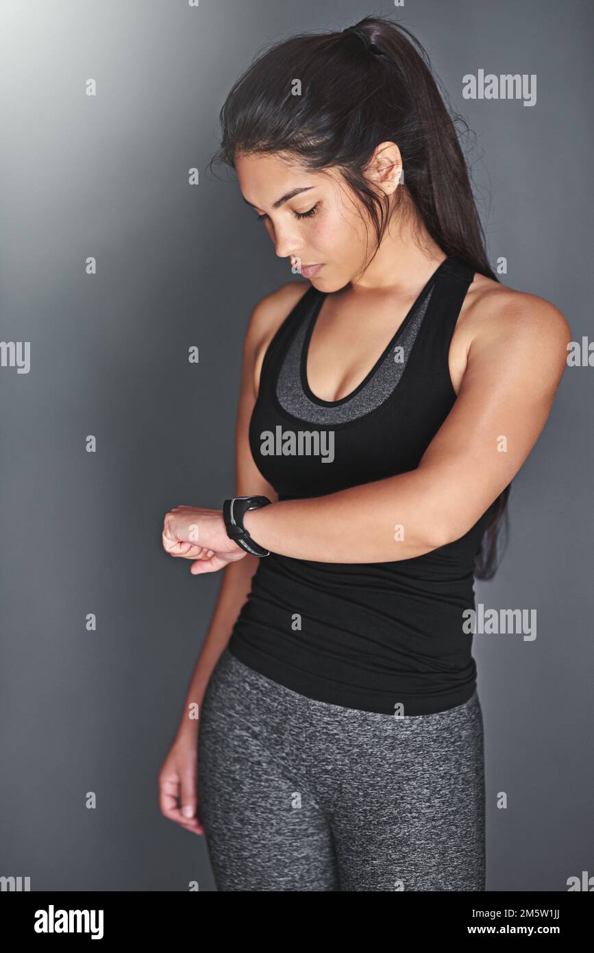 Sie überwacht ihren Fortschritt. Eine fitte junge Frau in Sportkleidung, die auf ihre Uhr schaut. Stockfoto