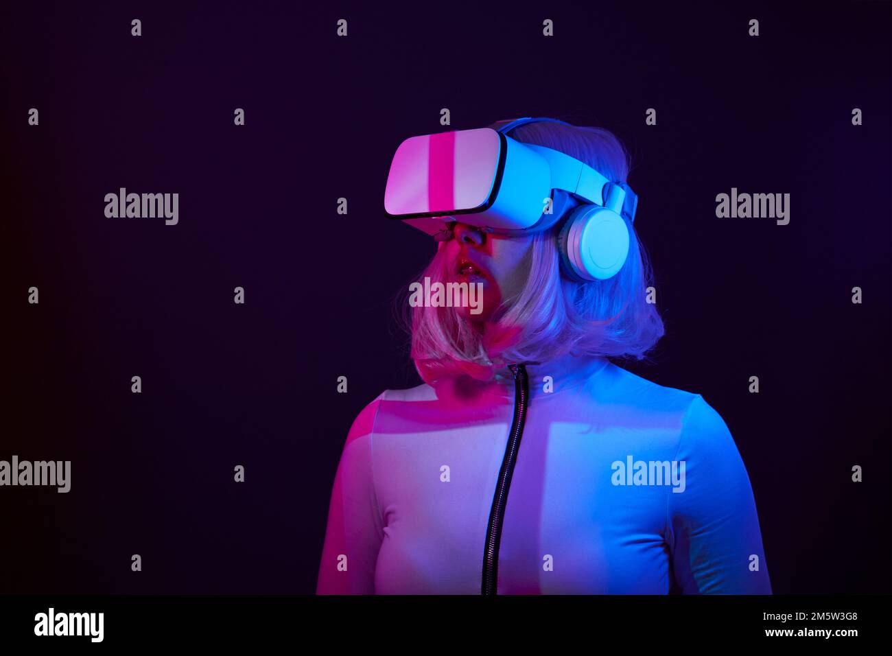 Eine Frau in Virtual-Reality-Brille in Neonfarben. Das Konzept der digitalen Technologie für Metaversum und Unterhaltung der Zukunft. Stockfoto