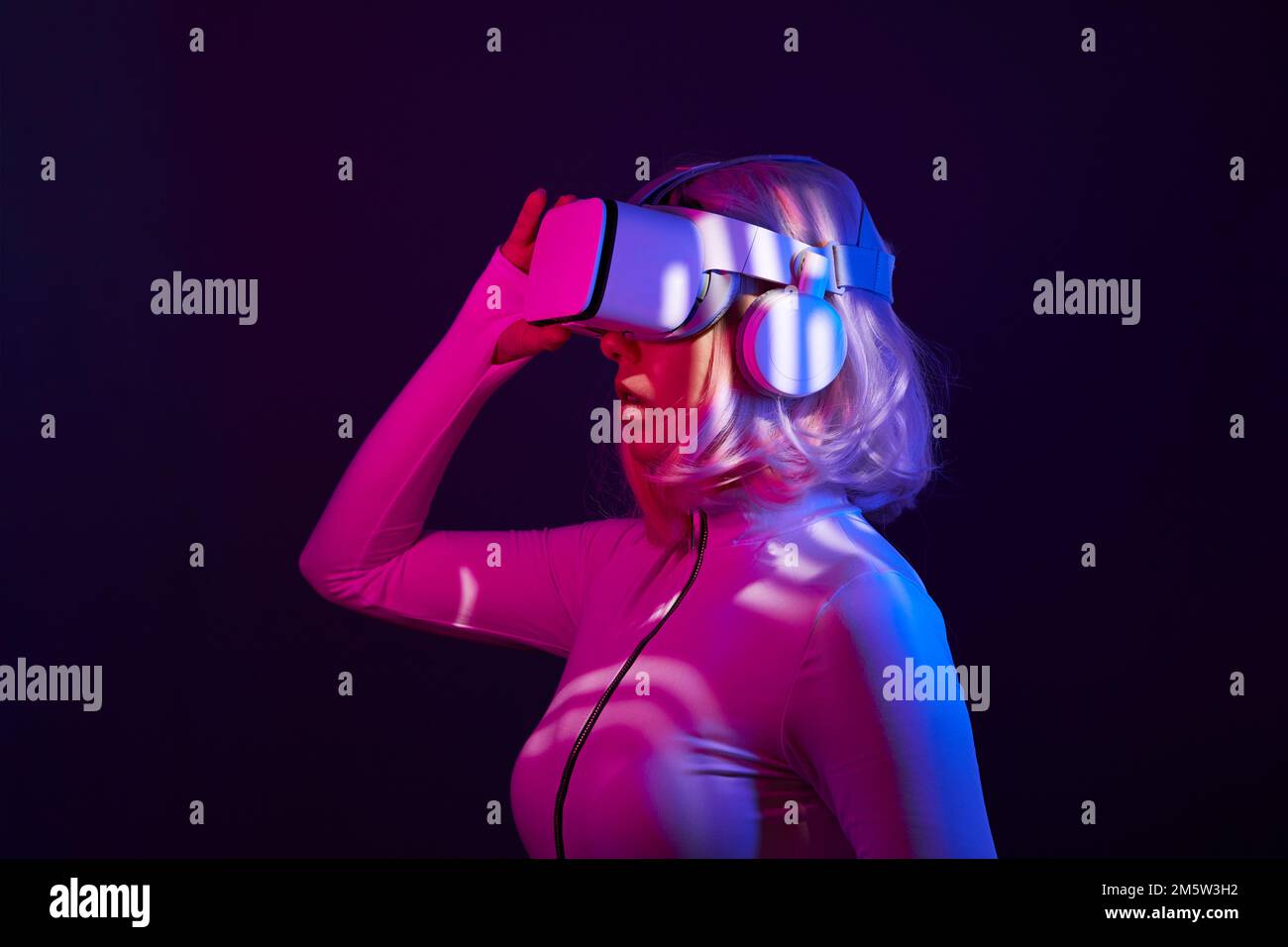 Eine Frau in Virtual-Reality-Brille in Neonfarben. Das Konzept der digitalen Technologie für Metaversum und Unterhaltung der Zukunft. Stockfoto