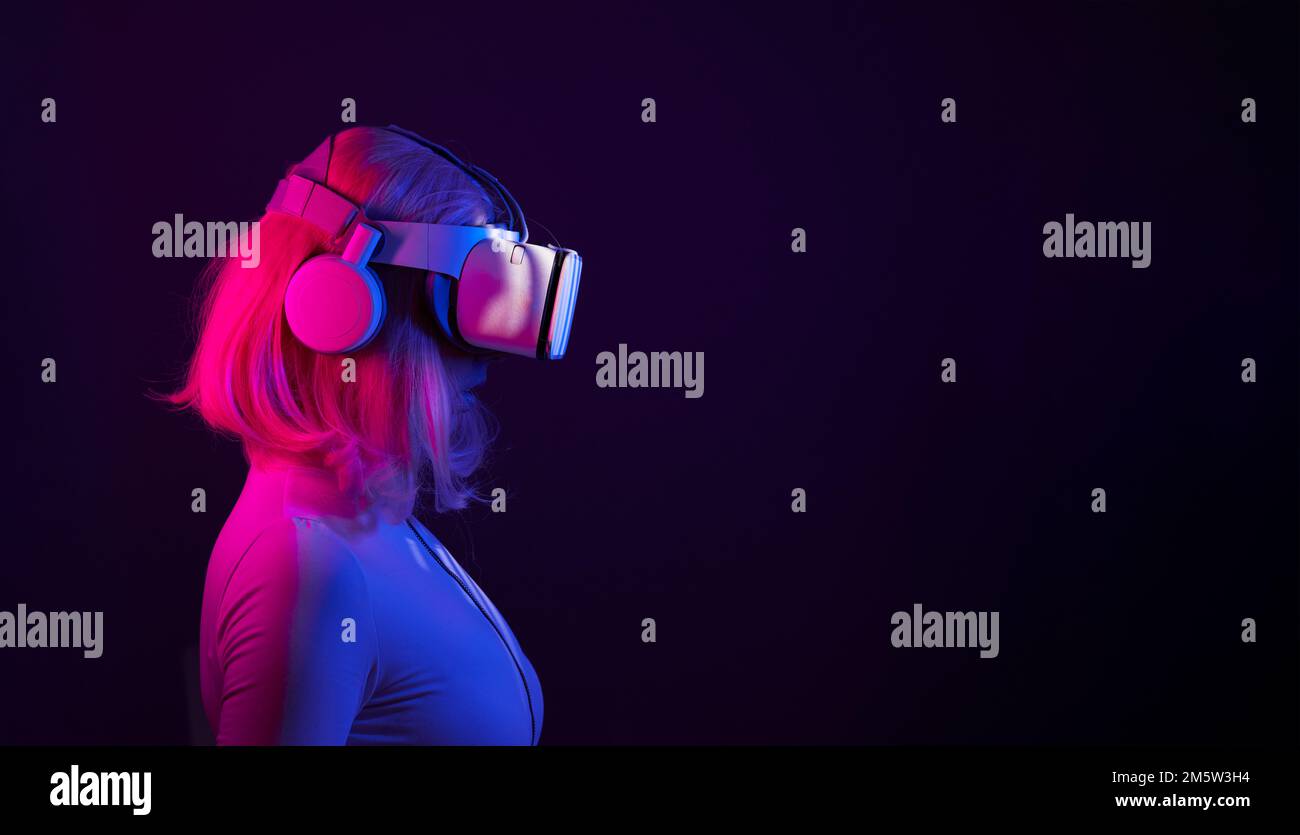 Eine Frau in Virtual-Reality-Brille in Neonfarben. Das Konzept der digitalen Technologie für Metaversum und Unterhaltung der Zukunft. Stockfoto