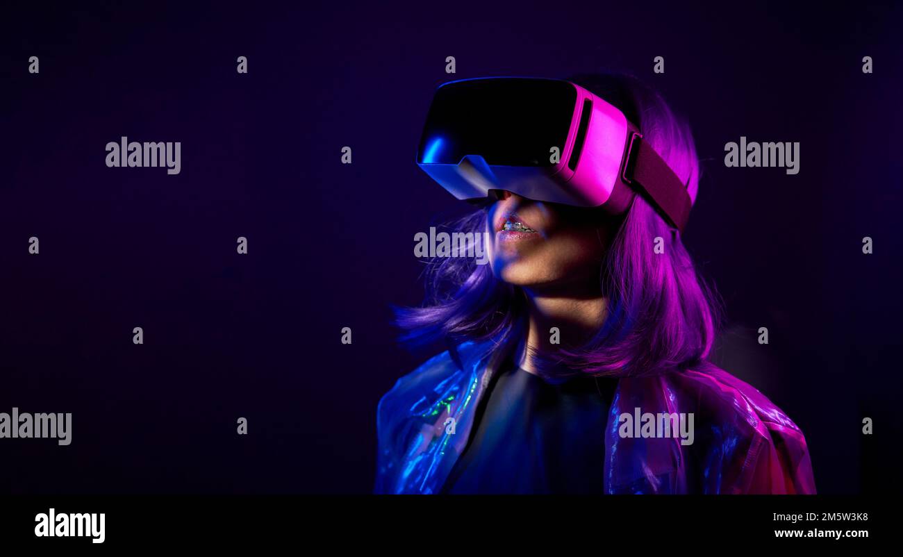 Eine Frau in Virtual-Reality-Brille in Neonfarben. Das Konzept der digitalen Technologie für Metaversum und Unterhaltung der Zukunft. Stockfoto