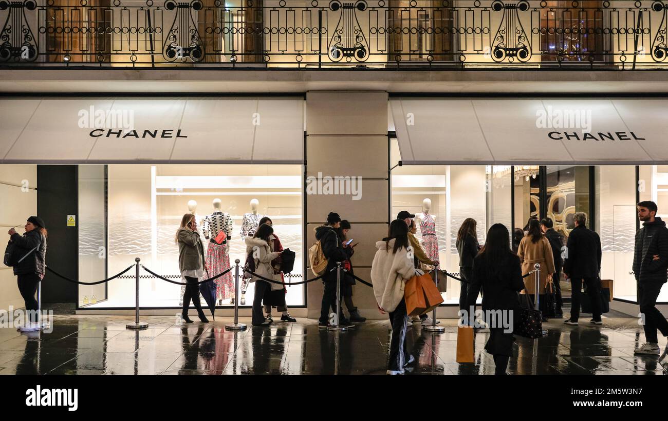 Chanel Flagship Store, Bond Street, Leute, die abends Schlange stehen, Regenreflexionen, London, Großbritannien Stockfoto