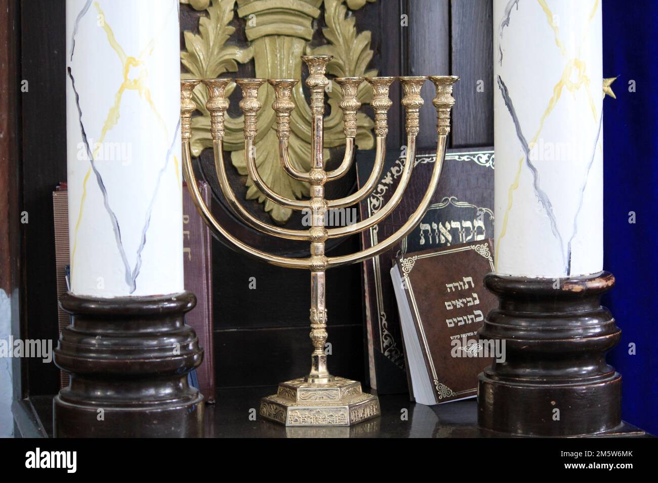 SAFED, ISRAEL - 8. MAI 2011: Dies ist eine Menora unter religiösen Büchern auf einem Regal in der Synagoge. Stockfoto