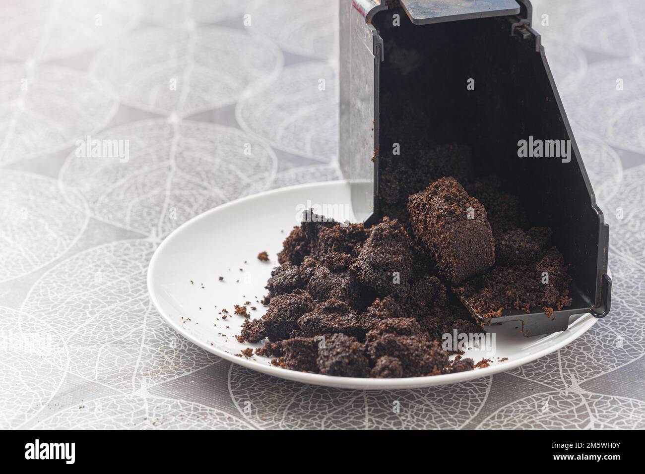 Gebrauchte Kaffeekapsel auf einem Teller mit nassgemahlenem Kaffee verschüttet. Abfall, ein-Tassen-Kaffee, Recycling-Konzept. Stockfoto