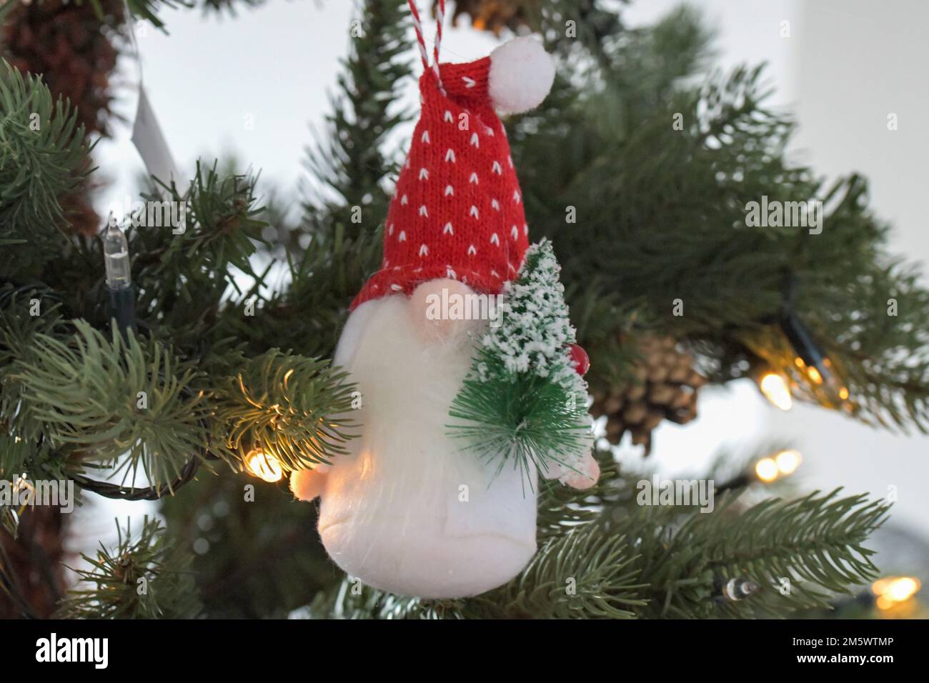 Ein Weihnachtsbaum, Gonk, Schmuck, hängt an einem Weihnachtsbaum mit einem Miniatur-Weihnachtsbaum und einem festlichen roten Hut Stockfoto