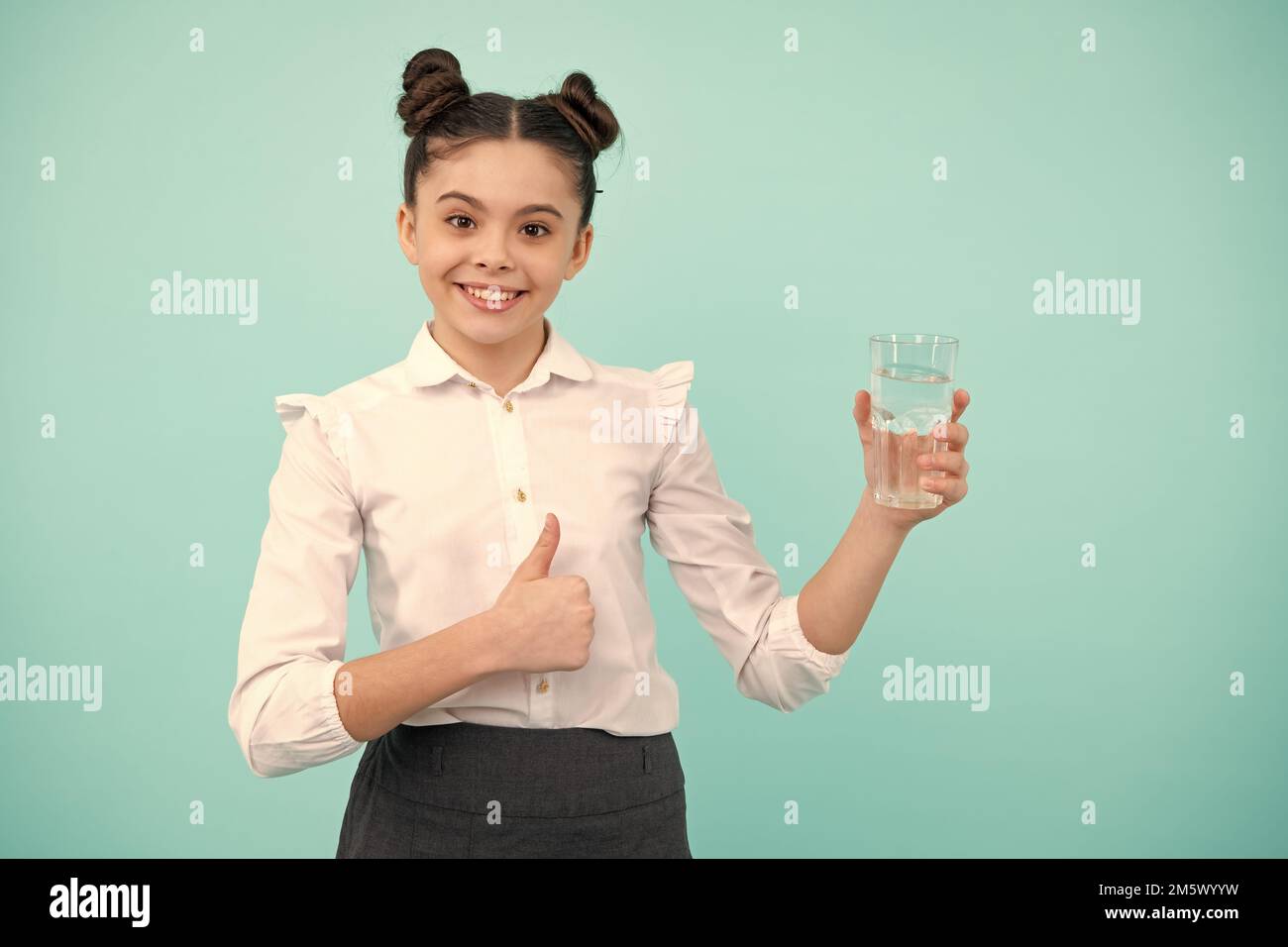 Teenager Mädchen Trinkwasser aus Glas auf blauem Hintergrund. Tägliche Gesundheit des Lebens. Trinken Sie Wasser für die Gesundheit und den Körper Gleichgewicht. Durstiges Kind, Austrocknung Stockfoto