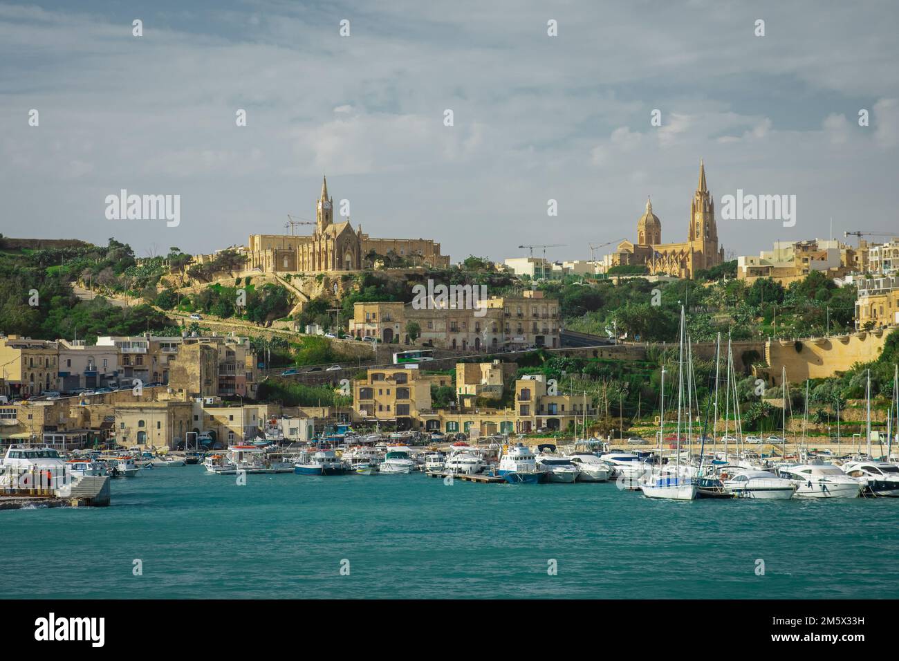 Eintritt zum Hafen von Mgarr auf der Insel Gozo mit sichtbarem Yachthafen, Kirchen und Booten vor Anker. Wunderschönes Stadtbild der Küstenstadt. Stockfoto