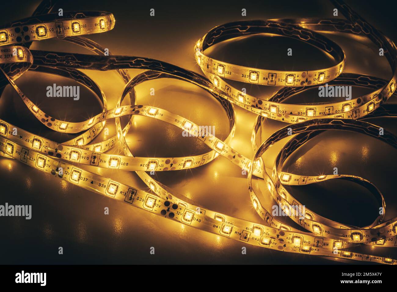 Von oben aus ein unverwirrter LED-Lichtstreifen mit leuchtenden Dioden auf einer glänzenden Oberfläche bei Dunkelheit Stockfoto