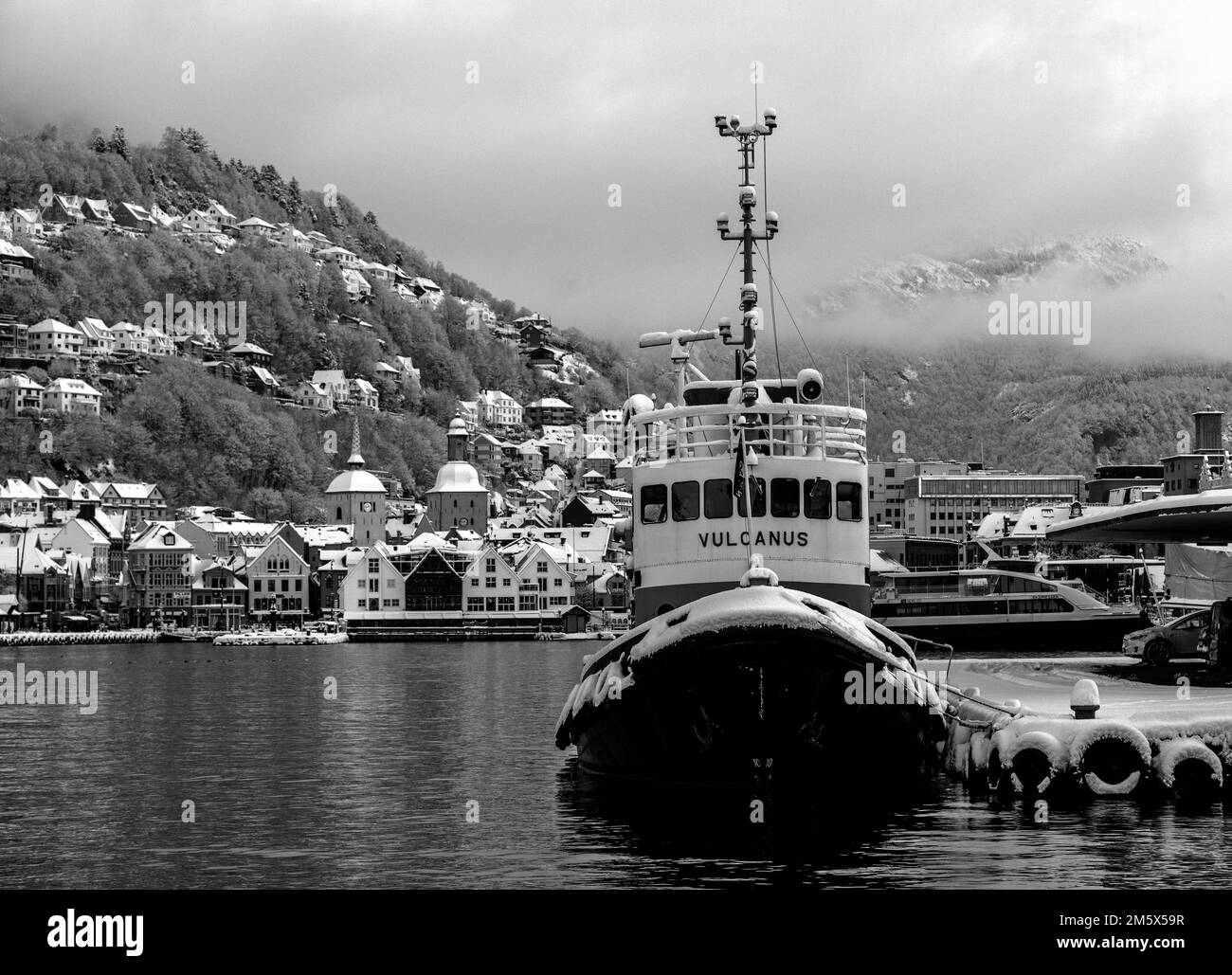 Winter in Bergen, Norwegen. Ein alter Schlepper, Vulcanus, im Hafen vor Anker. Zachariasbryggen und Ulriken im Hintergrund Stockfoto