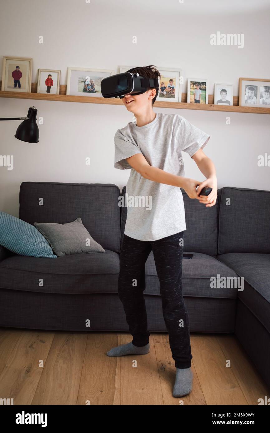 Junge, der Spaß beim Spielen von Simulationsspielen hat, mit Virtual-Reality-Headset und Controller. Kinder und modernes Technologiekonzept. Stockfoto