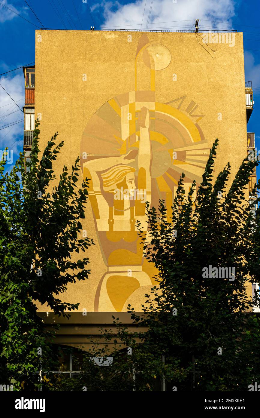 Wandbild mit einer Frau aus Kasachstan. Kasachisches Wandbild, das eine Arbeiterin darstellt. Karaganda, Kasachstan. Sowjetisches konstruktivistisches Wandbild Stockfoto