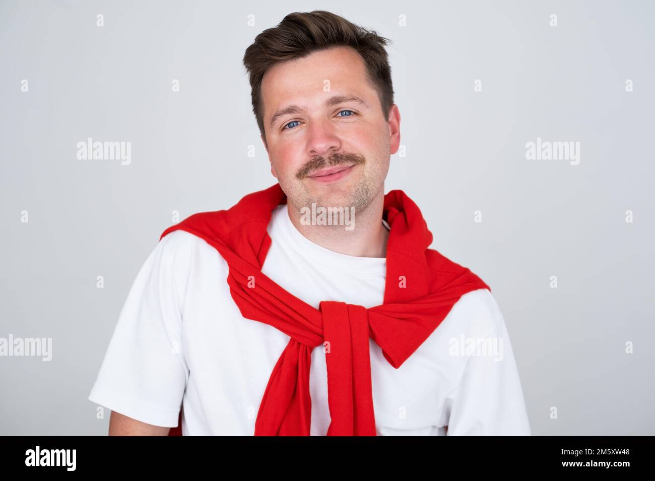 Porträt eines braunen, lächelnden, gutaussehenden Mannes mit Schnurrbart. Grauer Hintergrund. Stockfoto