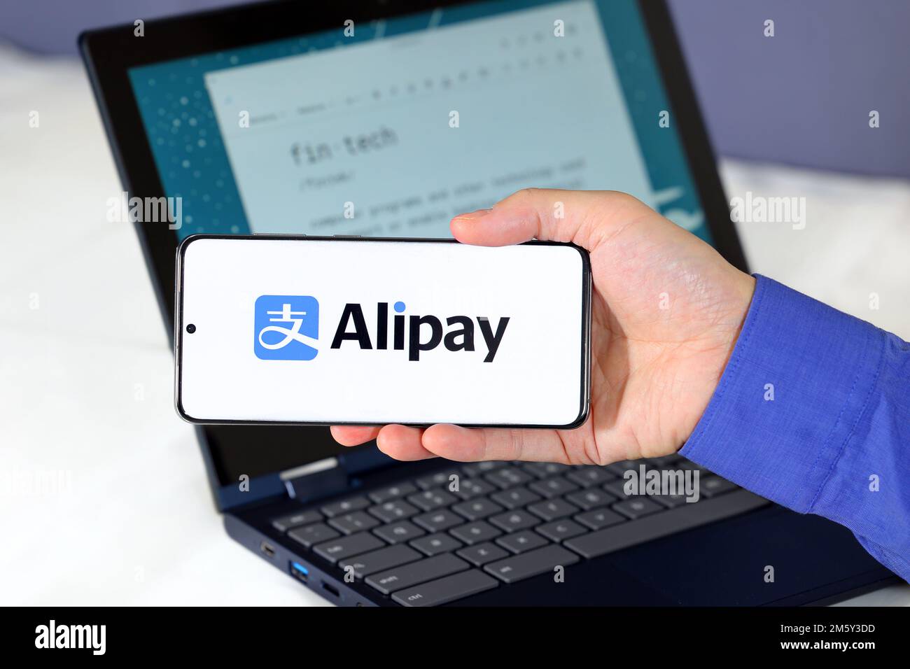 Alipay-Logo auf einem Smartphone vor einem Computer. Alipay 支付宝 ist ein digitaler Zahlungsdienst für mobile Geldbörsen mit Sitz in China. Stockfoto