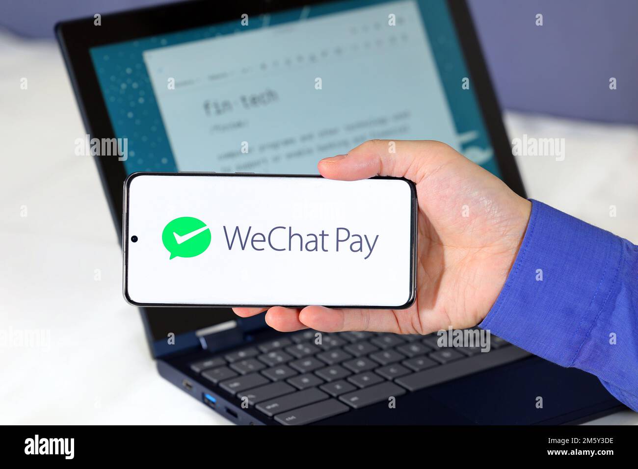 Logo von WeChat Pay auf einem Smartphone vor einem Computer. WeChat Pay 微信支付 ist ein digitaler Zahlungsdienst für mobile Geldbörsen mit Sitz in China. Stockfoto