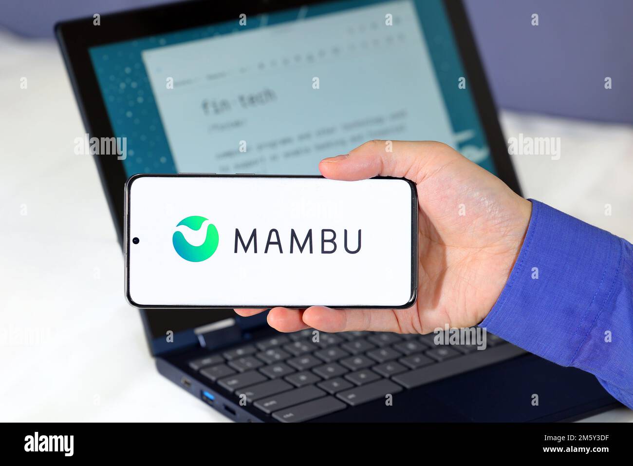 Logo von Mambu auf einem Smartphone vor einem Computer. Mambu ist ein Fintech-Unternehmen, das sich auf Cloud-Banking-Software als Service spezialisiert hat. Stockfoto