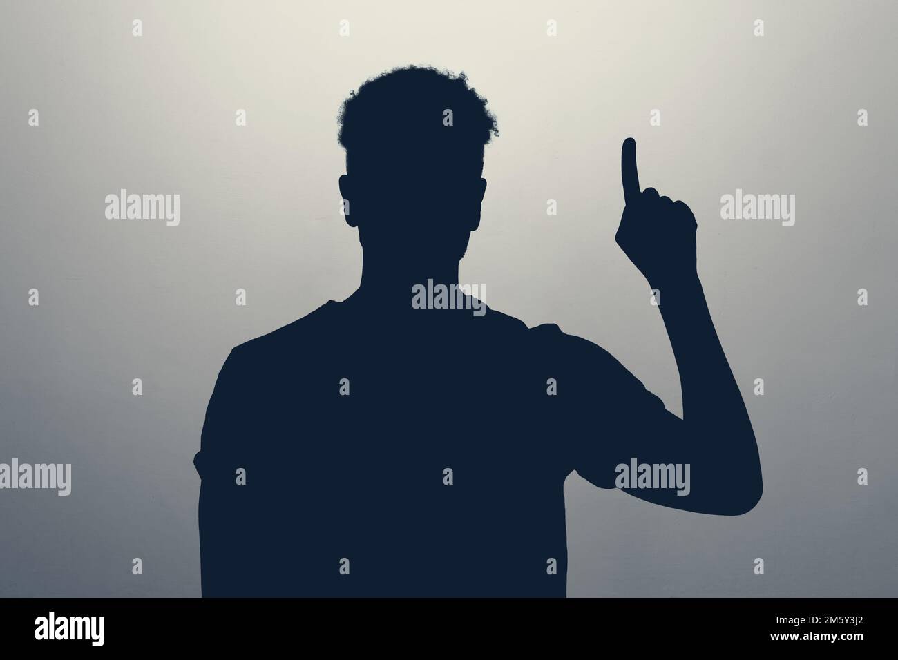 Die Silhouette eines Mannes, der mit isoliertem Finger auf grauem Hintergrund nach oben zeigt. Stockfoto