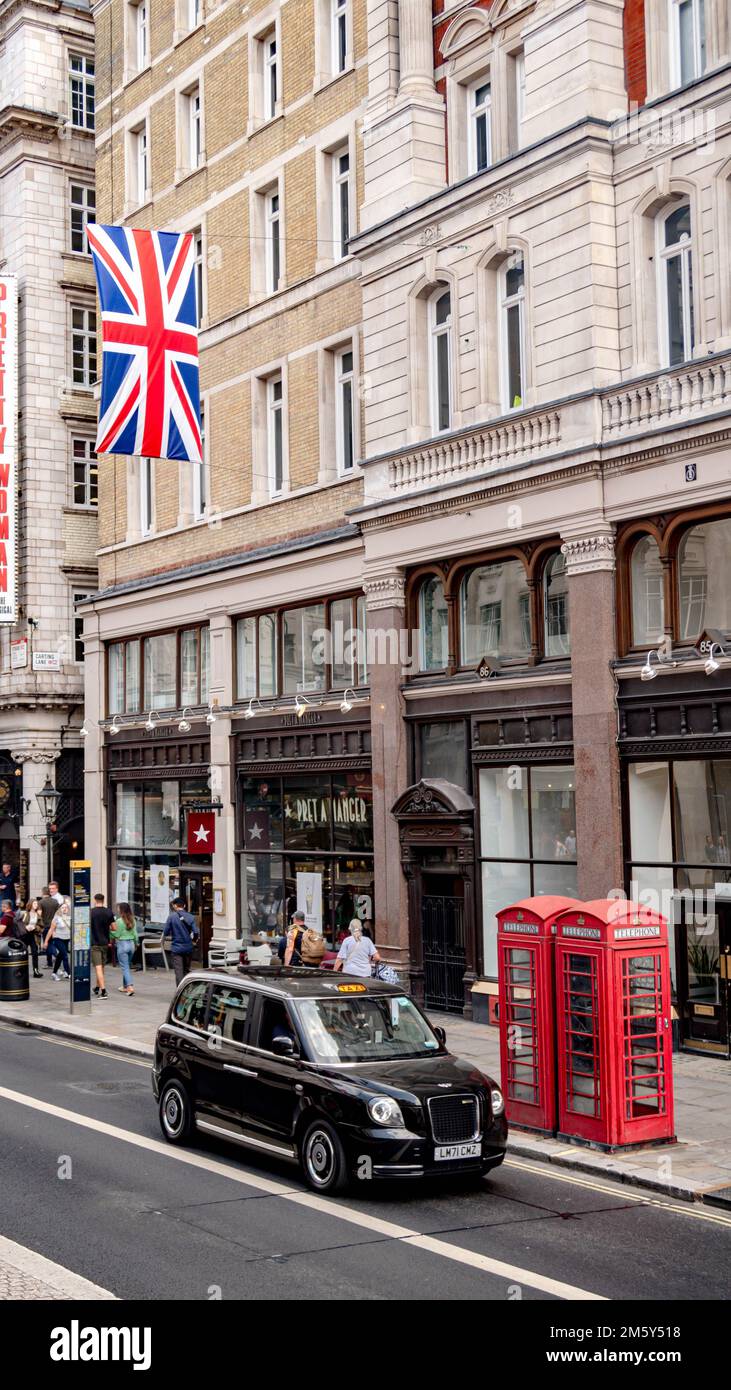 Das Londoner Stadtzentrum mit einem schwarzen Taxi und einer roten Telefonzelle, über der der Union Jack hängt Stockfoto