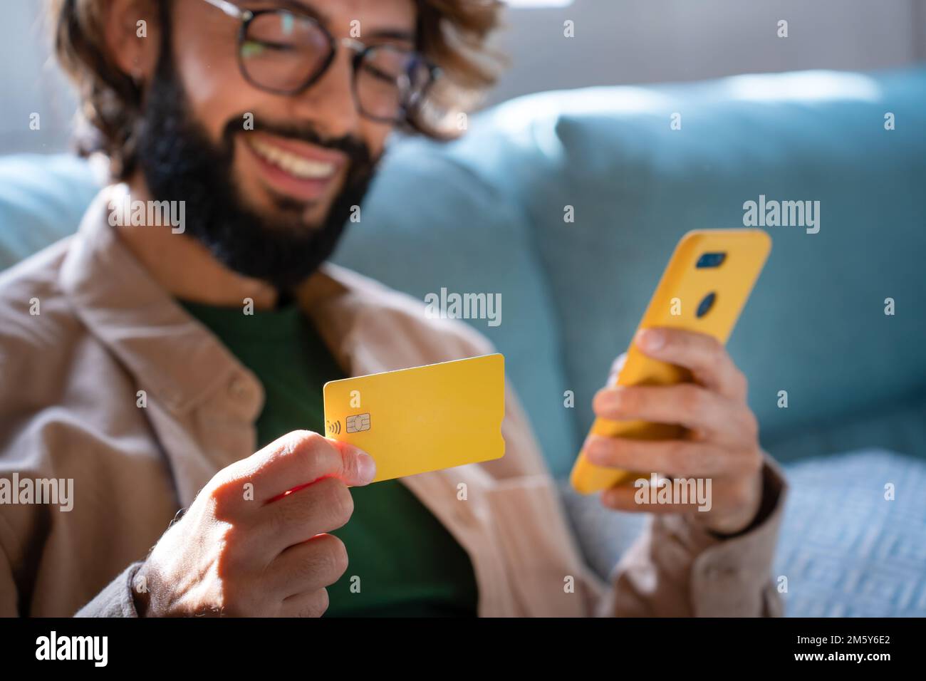 Glücklicher Kaukasier, der online einkauft, mit Smartphone und Kreditkarte einkauft, im Internet einkauft Stockfoto