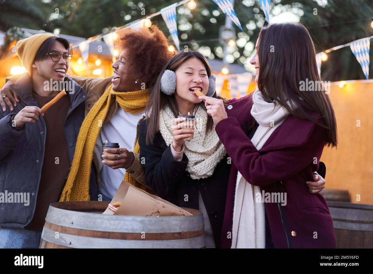 Fröhliche Freunde, die nachts im Freien Schokolade mit Churros Street Food essen Stockfoto