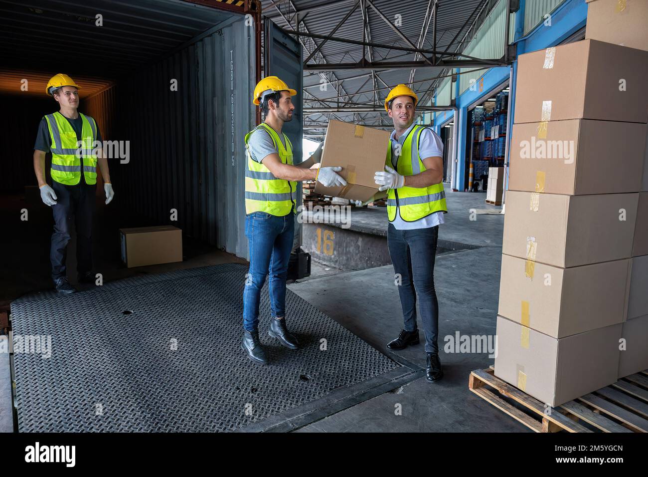 Arbeiter tragen Karton aus 40 Fuß Stahlcontainer auf dem Anhänger-Lkw-Parkplatz im Lager Stockfoto