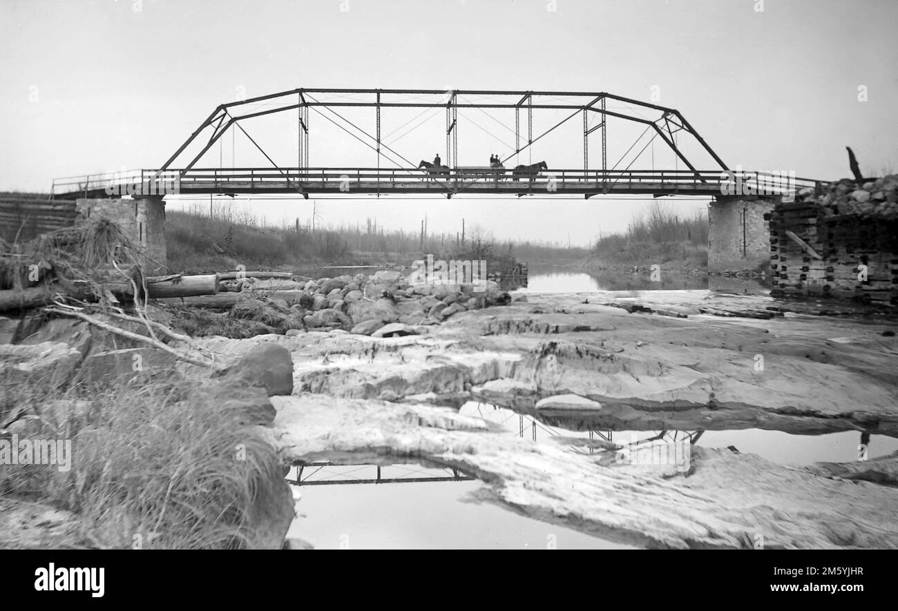 Pferde und Buggys überqueren eine frühe Brücke über einen Fluss in Pennsylvania, Kalifornien. 1900. Stockfoto