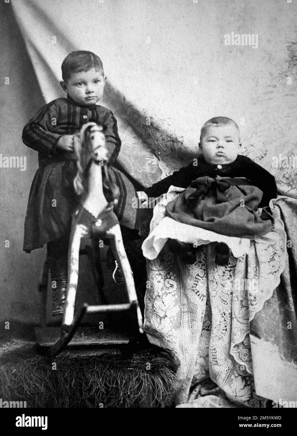 Ein Kleinkind und ein Baby posieren zusammen im Studio eines Fotografen, ca. 1890. Stockfoto
