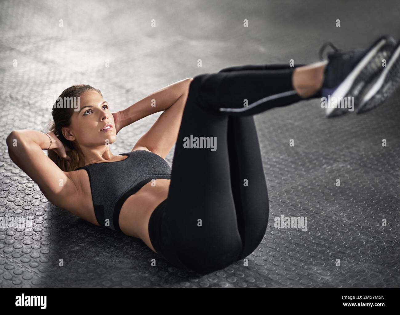 Der perfekte Körper braucht Arbeit. Eine junge Frau, die im Fitnessstudio Sit-ups macht. Stockfoto