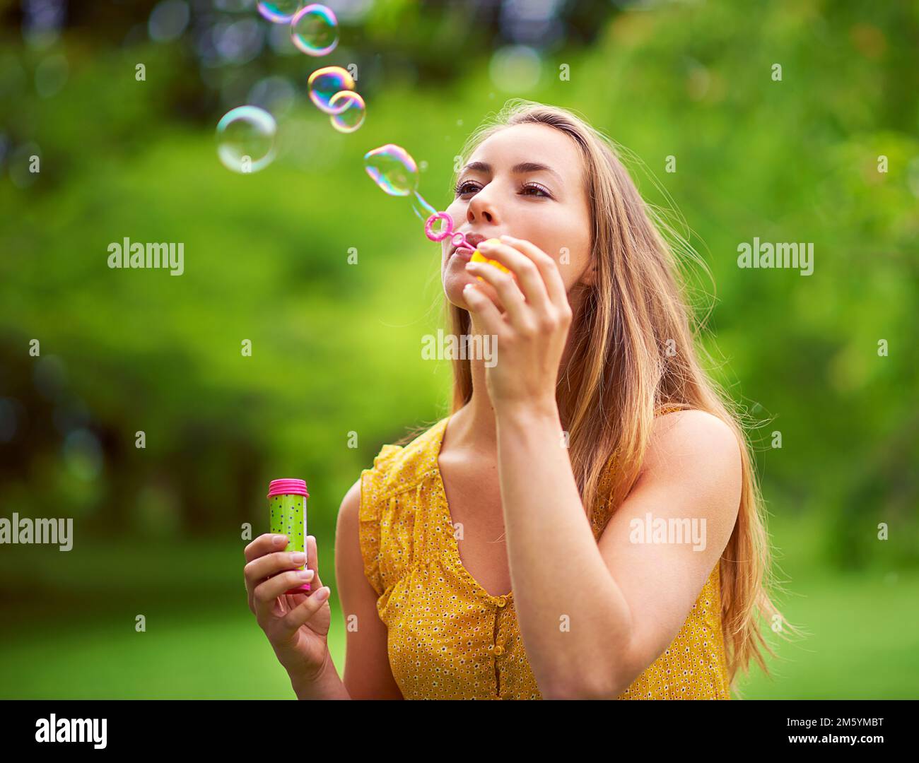 Verlier deine Probleme, Blase ein paar Blasen. Eine sorglose junge Frau, die im Park Blasen bläst. Stockfoto