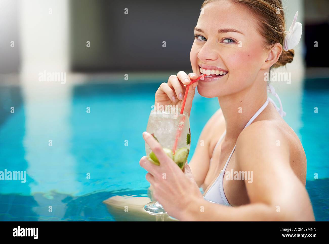 Der Geschmack des Sommers. Porträt einer attraktiven jungen Frau, die einen Cocktail am Pool schlürft. Stockfoto