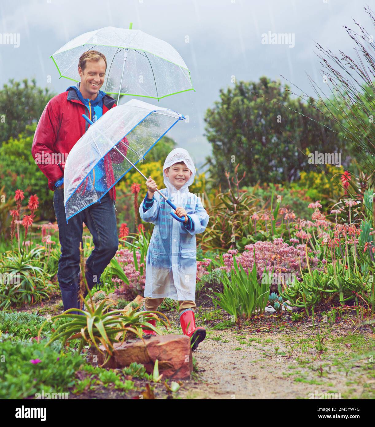 Unser Garten liebt den Regen. Ein Foto von einem Vater und seinem Sohn, wie er im Regen nach draußen geht. Stockfoto