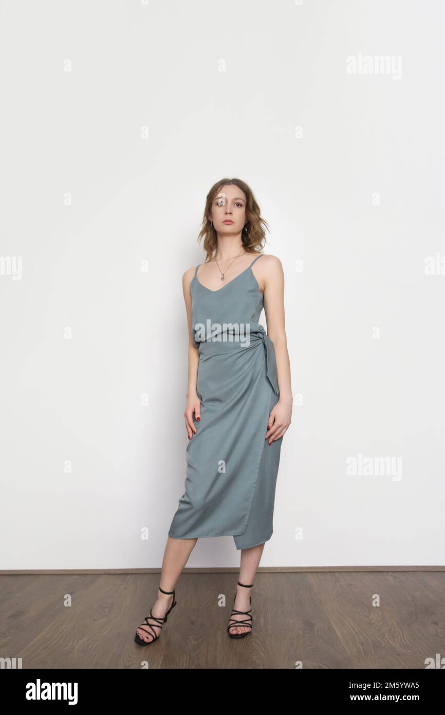 Weibliches Model mit blaugrauem Trägeroberteil aus Seide und gewickeltem Midi-Rock. Stylisches einfarbiges Sommeroutfit. Modestudio-Aufnahme. Stockfoto